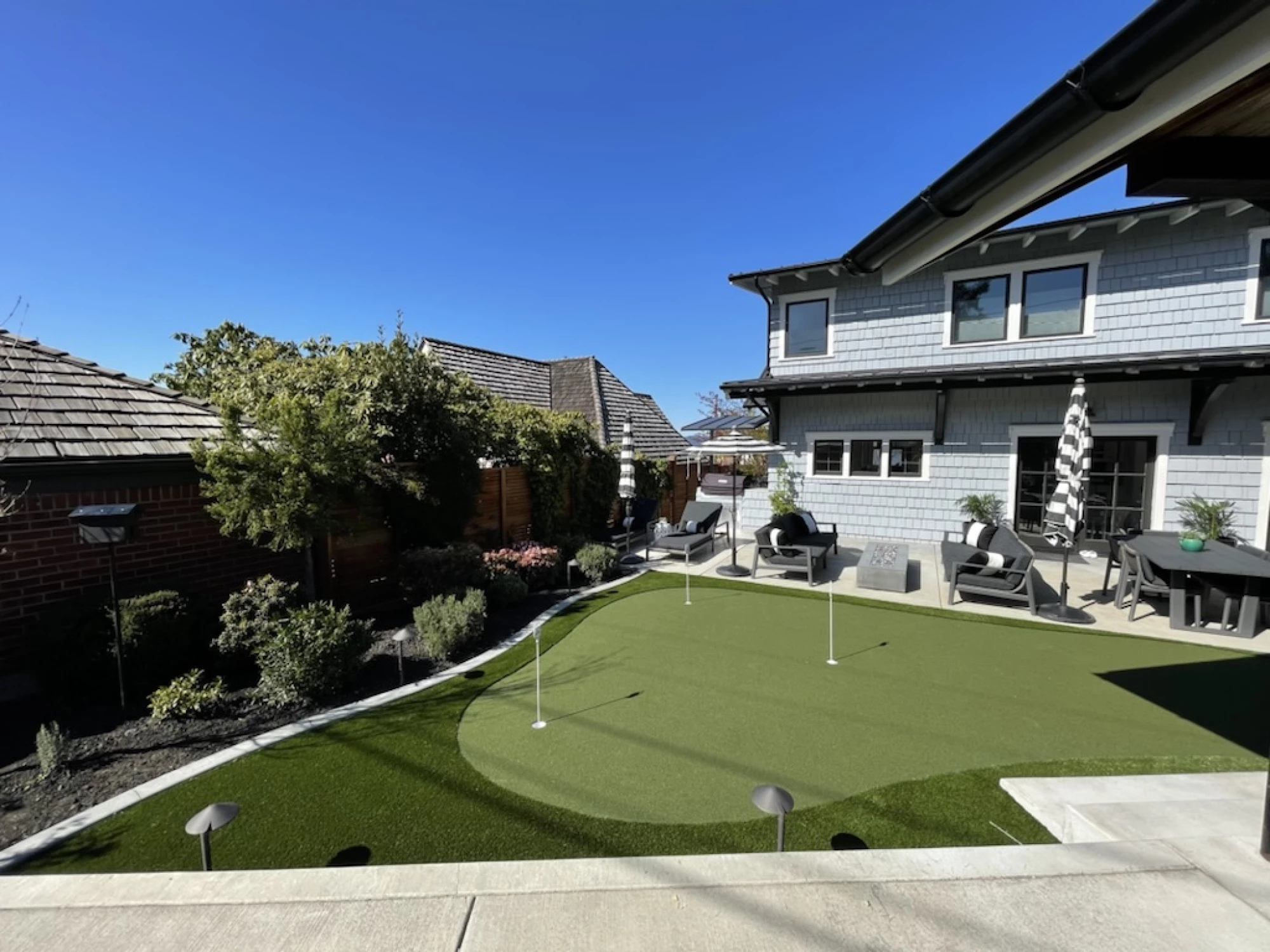 Artificial turf putting green with fringe installed in Tacoma, WA front yard surrounded by landscape lighting.